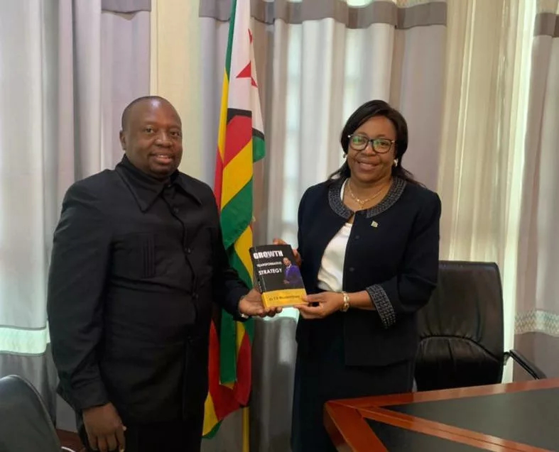 Dr T. Muzamhindo hands over his book to Professor Charity Manyeruke, Zimbabwe's Ambassador to Rwanda